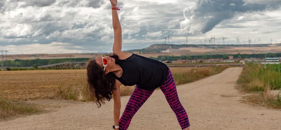 Outdoor fitness scene of a woman stretching on a dirt path in Soto de Cerrato amidst scenic landscapes.